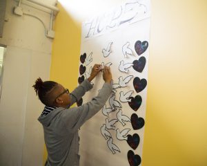 Student puts paper doves and hearts on wall