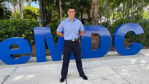 Portrait of Mikael Alfonso standing in front of MDC sign