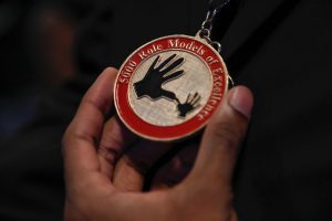 Close up of hand holding medal with inscription 5000 Role Models of Excellence
