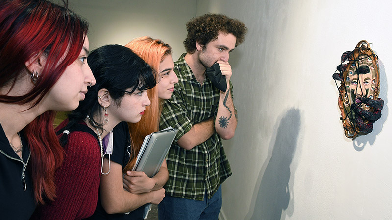 four students looking at artwork on wall