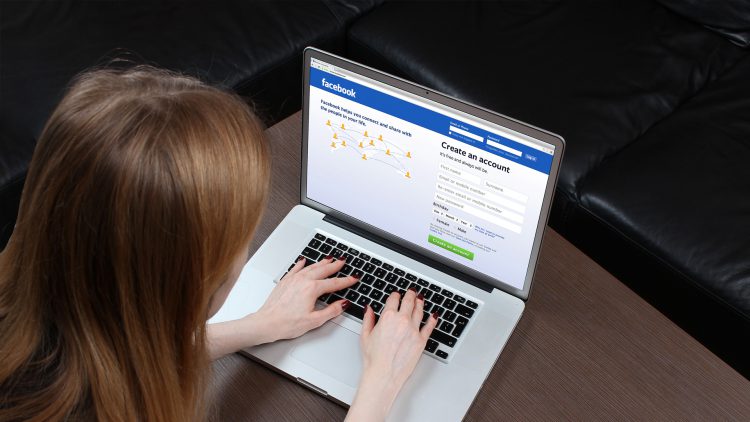 Woman logging into Facebook on laptop