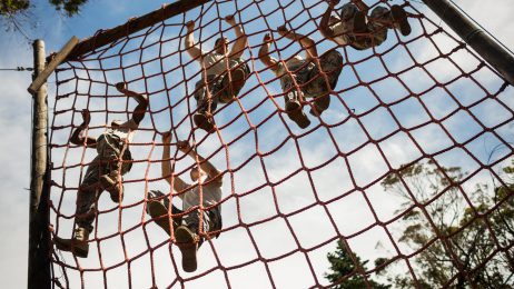 Soldiers in training climbing rope