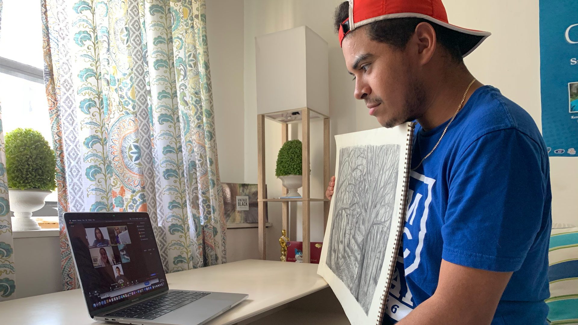 Male student showing drawing on video call