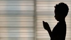 silhoutte of woman against the window using her cell phone