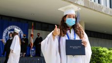 MDC alumna giving a thumbs up and showing her diploma
