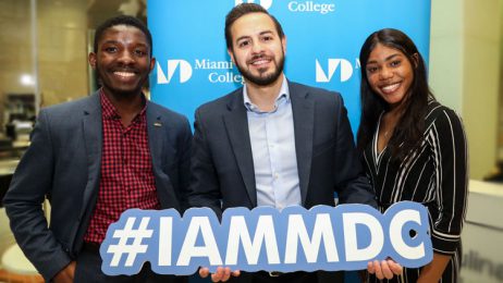 Giovanni R. Castro and two other alumni holding a sign that reads #IAMMDC