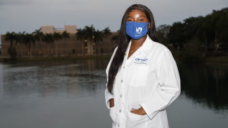 Female student in white lab coat standing outdoors