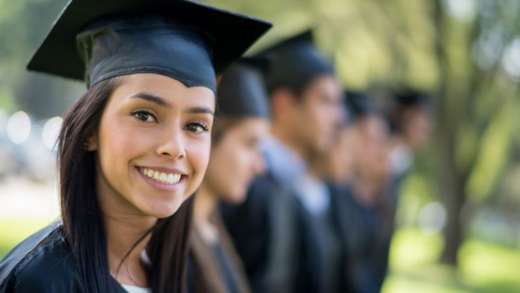 Female student with graduation gown in foreground with other students in back