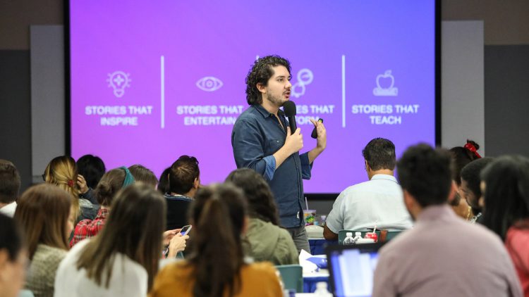 Male instructor speaking into a microphone in front of a class