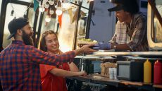 A man and a woman receiving a plate of food from a foodtruck
