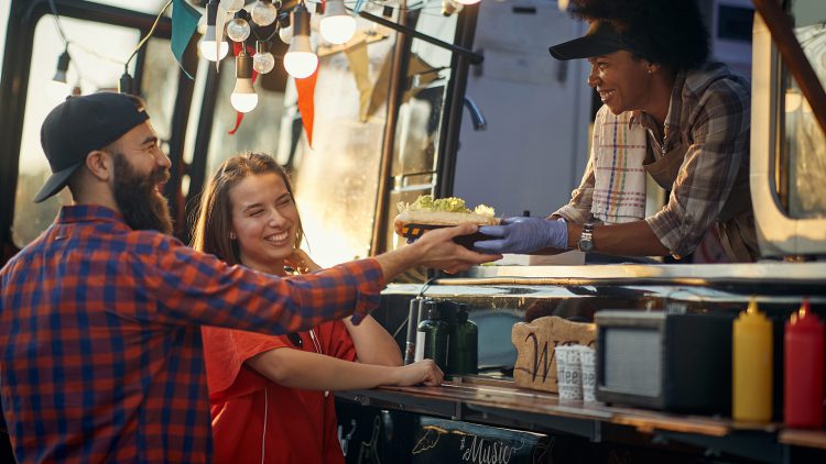 A man and a woman receiving a plate of food from a foodtruck