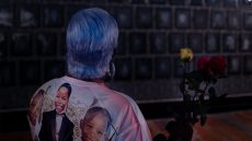 Photo from behind of woman with blue hair looking at artwork