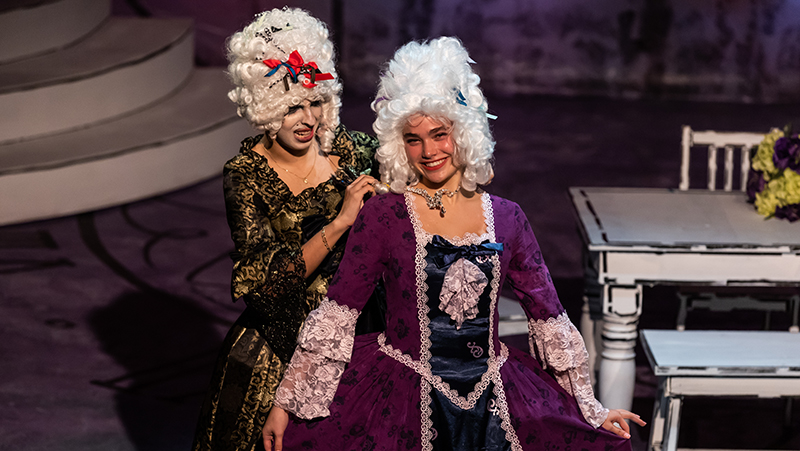 Two students on stage performing in Cinderella dressed in period costume.
