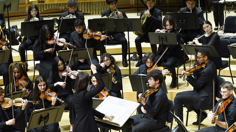 Conductor and students symphony orchestra performing on stage