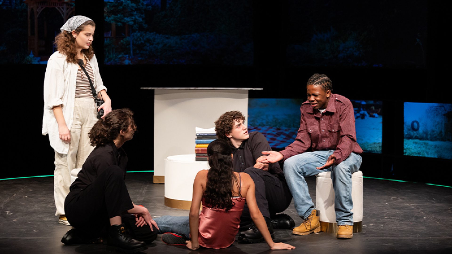 Five student actors on stage performing.