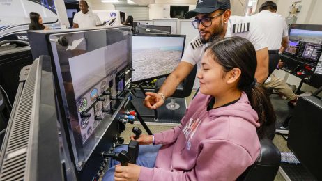 Female student with instructor sitting at flight simulator