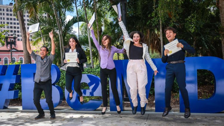 Five winning students jumping in the air