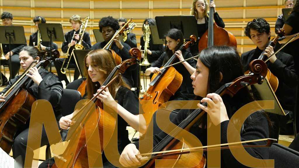 Student orchestra playing their instruments on stage.