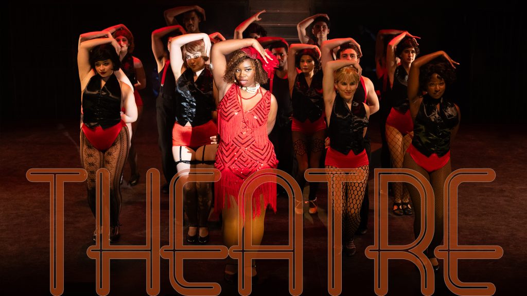 Ensemble of student actors performing on stage dressed in black and red.