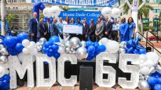 The college president with others standing on a stage outdoors celebrating I AM MDC Day