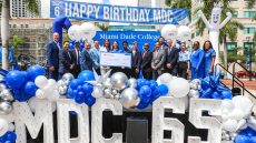 College president with others standing on an outdoor stage with a check