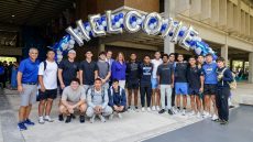 Students with the college president under an arch of balloons