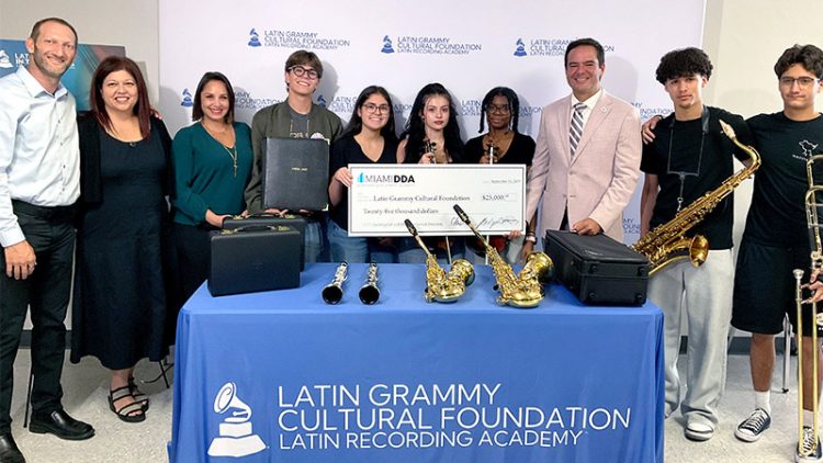 Group of people standing behind a table with instruments holding a giant check.