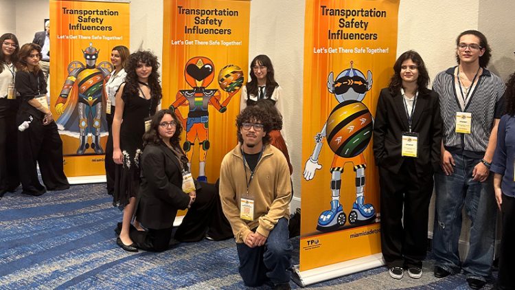 Group of people standing or sitting by three colorful upright banners.