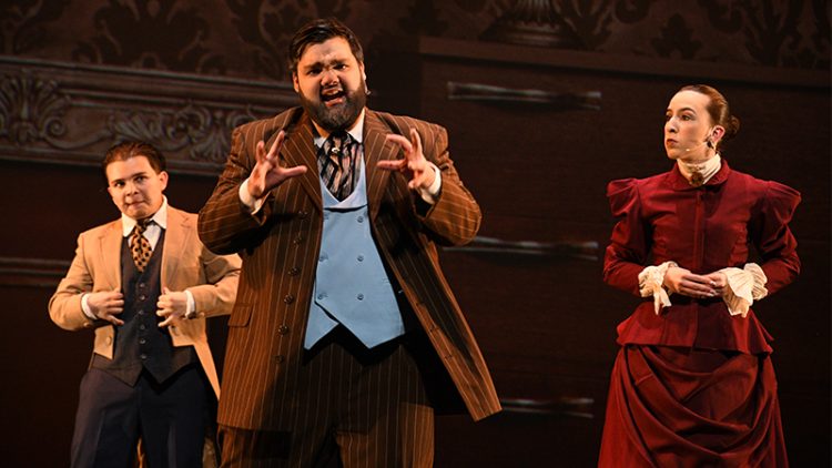 Three people on stage acting in period costumes.