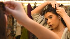 Person fixing hair in front of mirror in dressing room.