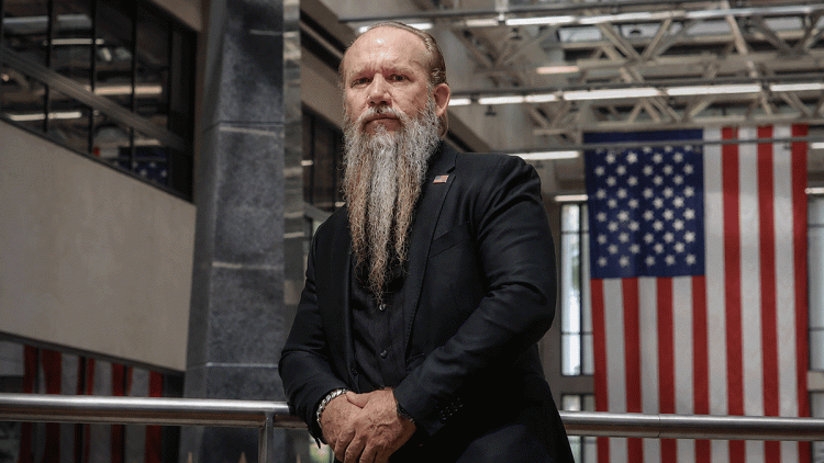 Professor standing in front of his sculpture which honors fallen soldiers.