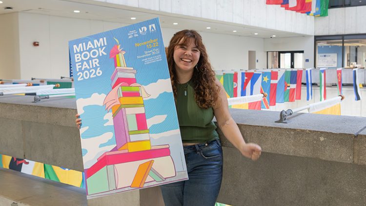 Girl in concrete building with various flags behind her holding a colorful poster.